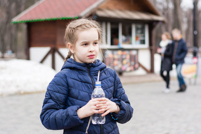 Cute girl holding a bottle with drinking water on the background of a food truck in a city park