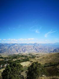 Scenic view of landscape and mountains against blue sky