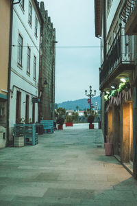 Empty street amidst buildings against sky in city