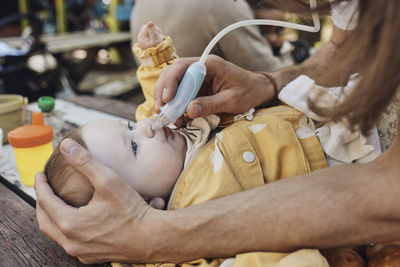 Father cleaning nose of toddler daughter through nasal aspirator