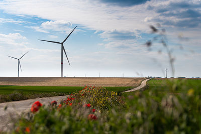 Wind turbines on field against sky