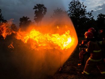 Fighters extinguishing fire on field at dusk 