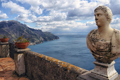 Statue by sea against sky