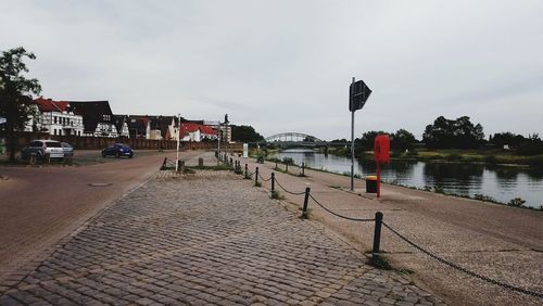 Street by river against buildings in city against sky