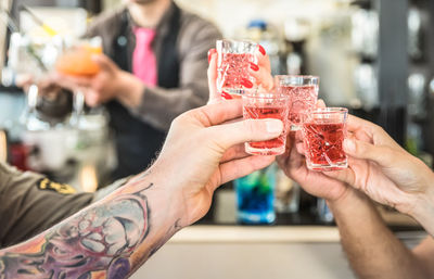 Cropped hands of friends toasting drinks in bar