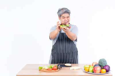 Woman holding apple while standing against white background