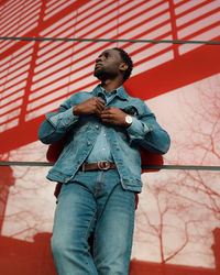 Low angle view of man standing against red wall