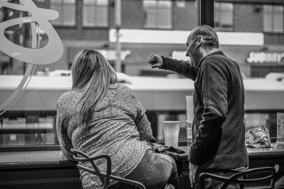 Rear view of man and woman sitting in bus