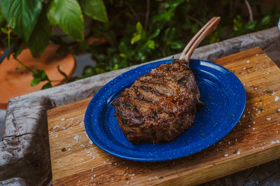 High angle view of steak in plate over cutting board