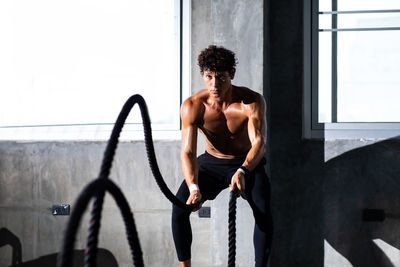 Man exercising with ropes in gym