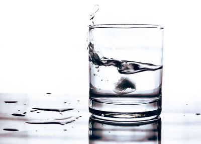 Close-up of water splashing in glass against white background