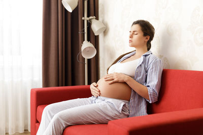 Young woman using mobile phone while sitting on sofa at home