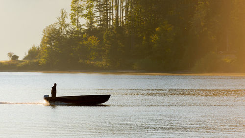 Man on boat in lake against sky
