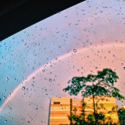Raindrops on glass window against sky