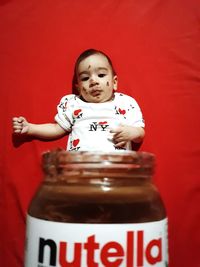 Portrait of girl with chocolate bottle against red background