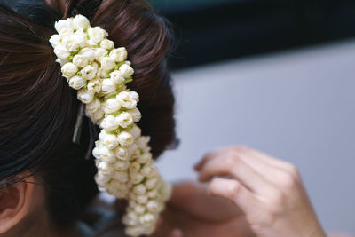 Cropped image of woman putting flower garland on bride