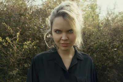 Portrait of beautiful young woman standing against plants