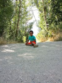 Young man using mobile phone while sitting on tree