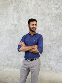 Portrait of young man standing against wall