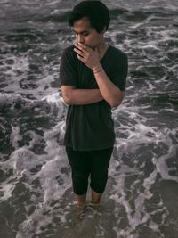 High angle view of young man standing in sea