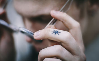 Close-up of teenage boy with tattoo holding eyeglasses