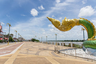 Statue by road against sky in city