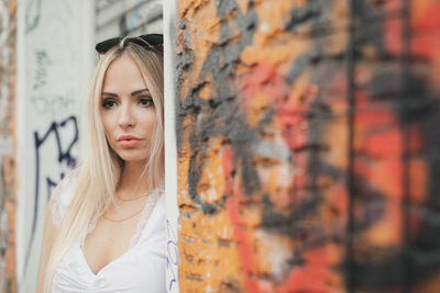 Portrait of young woman standing against wall