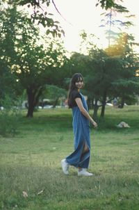 Portrait of young woman standing against trees at park