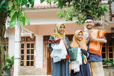 Portrait of smiling family greeting outside house