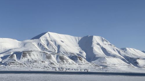 Scenic view of snowcapped mountains against clear blue sky- svalbard 