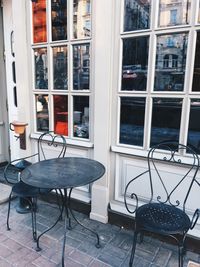 Empty chairs and tables in cafe against building