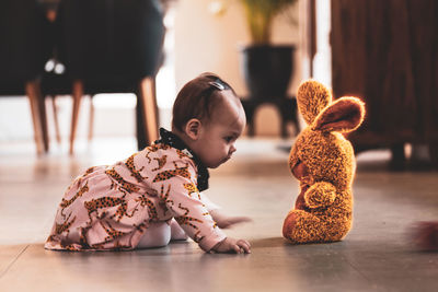 Cute baby girl with toy on floor at home