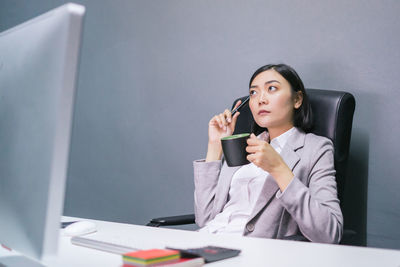 Young woman using mobile phone while sitting on table