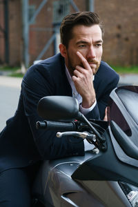 Man looking away while sitting on motorcycle outdoors