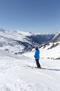 Person skiing on snowcapped mountain against clear sky