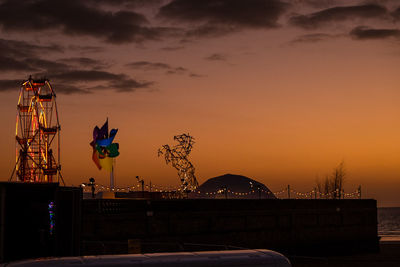 Ferris wheel against sky at sunset