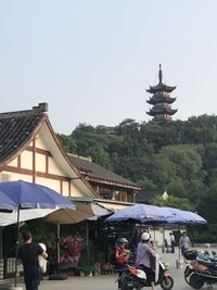 People in temple by building against clear sky