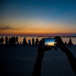 People photographing against sky during sunset