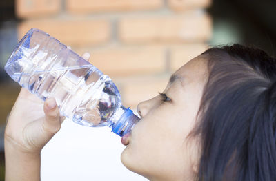 Midsection of a child drinking from a water bottle