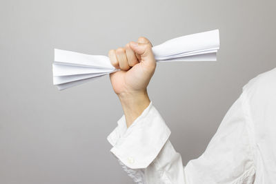 Close-up of man holding paper against white background