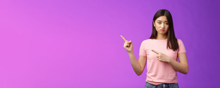 Young woman with arms raised against blue background