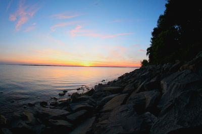 Scenic view of rocky coastline and sea at sunset