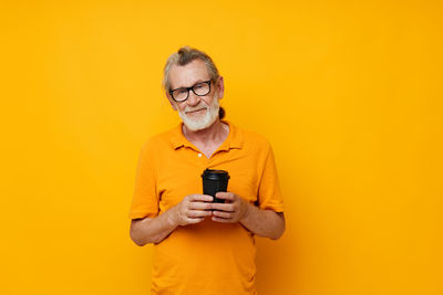 Young woman using mobile phone against yellow background