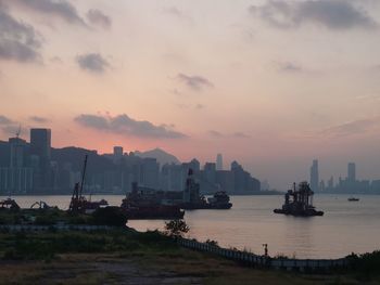 Scenic view of sea by buildings against sky during sunset