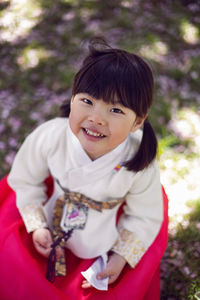 Korean girl child in a national costume walks in a garden with cherry blossoms in spring