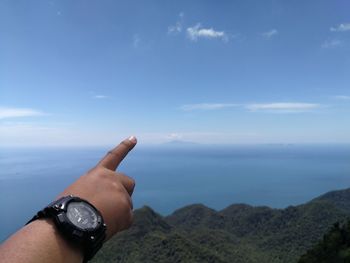 Close-up of hand on mountain against sky