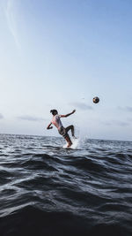 Low angle view of person paragliding in sea against sky