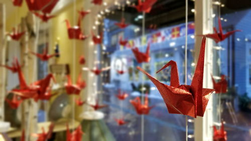 Origami paper cranes hanging against glass window