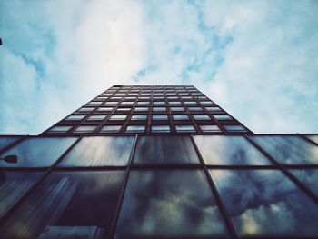 Low angle view of office building against cloudy sky
