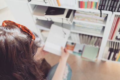 High angle view of woman sitting in front of bookshelf